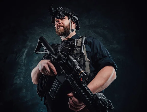 Soldier with helmet and vest stays holding a rifle in dark background — Stock Photo, Image