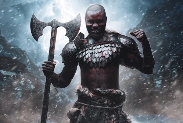 Nordic barbarian with black skin and axe in snowstorm in mountains — Stock Photo, Image