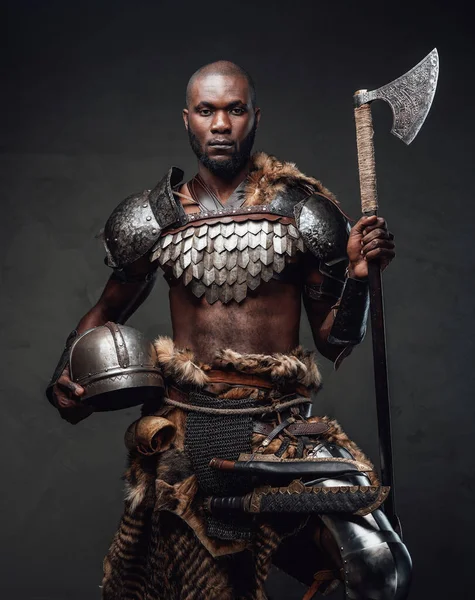 Wild barbaric person with black skin wielding an axe posing in dark background — Stock Photo, Image