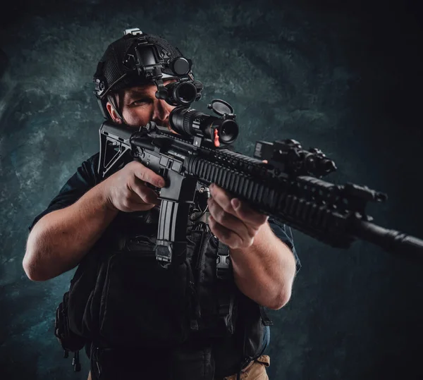 Gevaarlijke en gewapende soldaat richt een machinegeweer op donkere achtergrond — Stockfoto