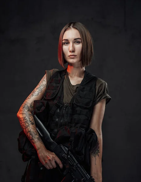 Getatoeëerde martiale vrouw in zwart harnas met aanvalsgeweer — Stockfoto