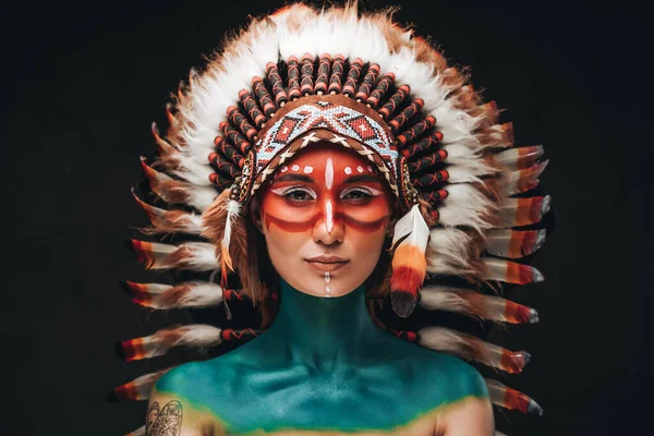 Vrouw geschilderd en gekleed in inheemse Amerikaanse stijl in studio — Stockfoto