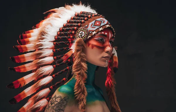 Tattooed trendy woman wearing national headwear from feathers — Stock fotografie