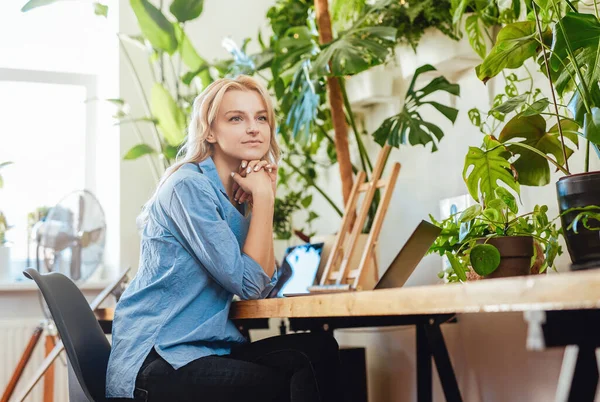 Trabalhadora de escritório feminina atraente e pensativa se senta à mesa com um laptop — Fotografia de Stock