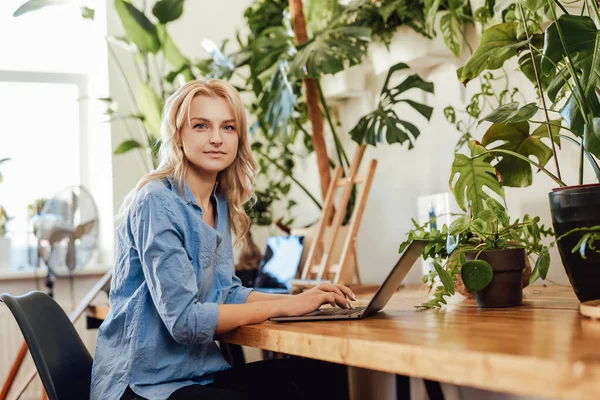 Trabalhadora de escritório feminina atraente e pensativa se senta à mesa com um laptop — Fotografia de Stock