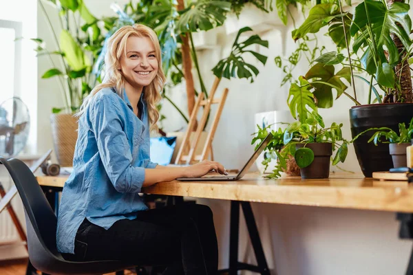 Joyful mulher empresária trabalha em seu laptop no escritório com plantas — Fotografia de Stock
