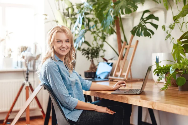 Joyful mulher empresária trabalha em seu laptop no escritório com plantas — Fotografia de Stock