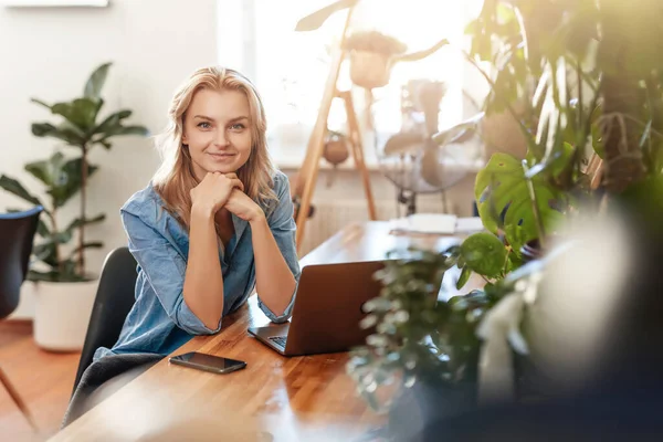 Pensée jeune femme pose dans la salle de bureau avec ordinateur portable à la table — Photo