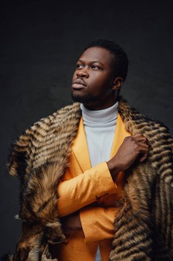 Kürk ve turuncu ceket giyen düşünceli siyah adam.