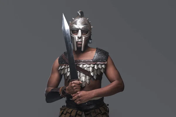 Heftiger Gladiator mit Schwert vor grauem Hintergrund — Stockfoto