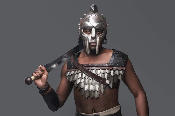 Gladiador violento com espada contra fundo cinza — Fotografia de Stock