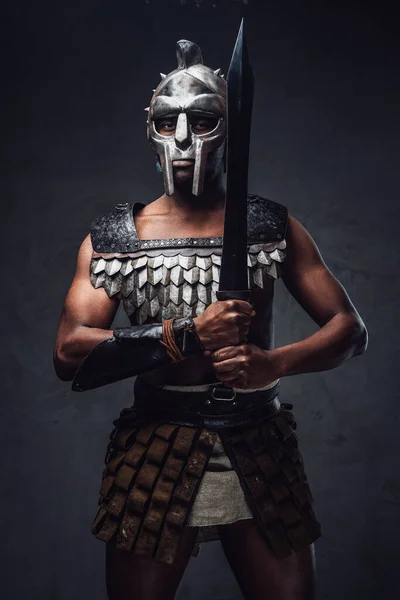 Proud antique gladiator with sword against dark background — Stock Photo, Image