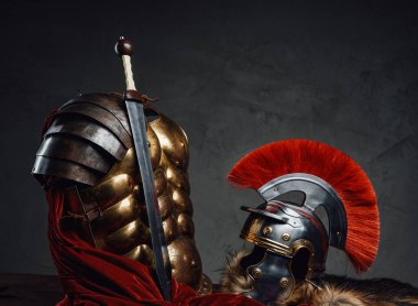 Kasklı ve kılıçlı zırhlı, karanlık arka planda.