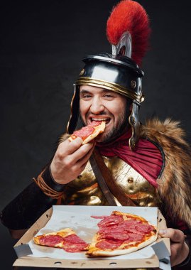 Satisfied roman soldier enjoys pizza against dark background clipart