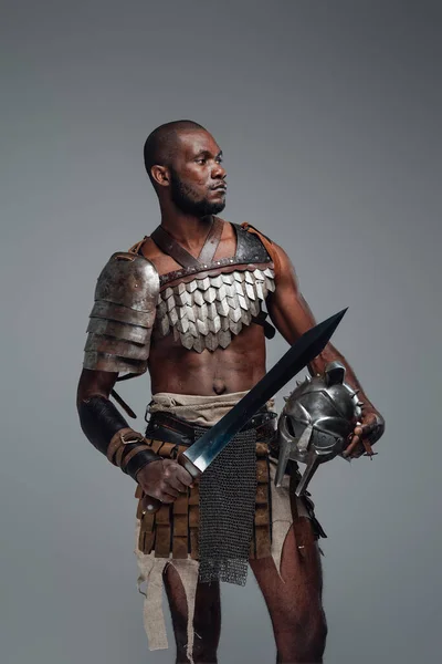 Африканский гладиатор с мечом на сером фоне — стоковое фото