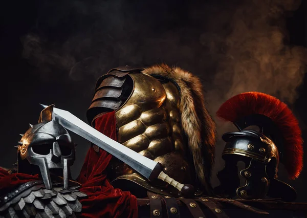 Armadura dourada entre gladiador e capacetes legionários — Fotografia de Stock