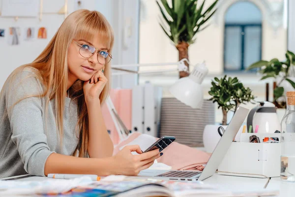 Empregadora bem sucedida sentada à mesa com um telefone no escritório — Fotografia de Stock