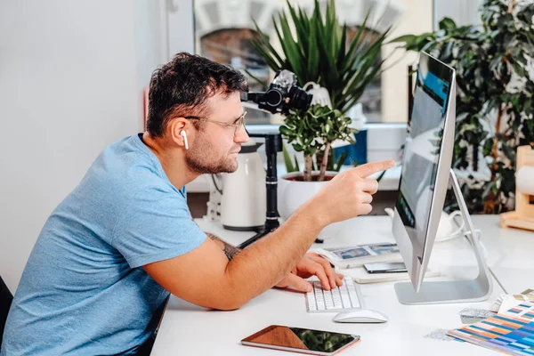 Vit man med glasögon poser sitter vid bordet med dator på kontoret — Stockfoto