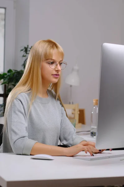 Zakenvrouw zit aan tafel kijkend naar computerscherm in kantoor — Stockfoto