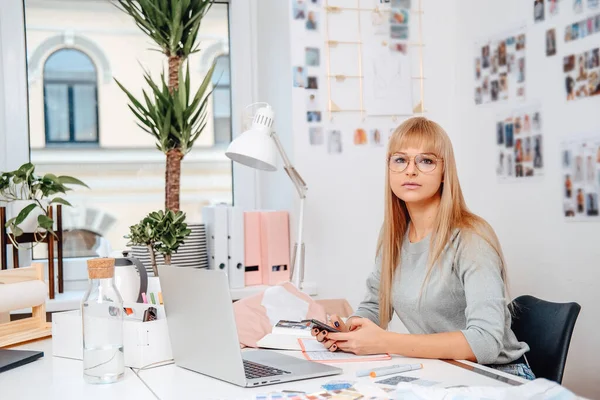 Kaukaska bizneswoman z telefonem komórkowym i laptopem w biurze — Zdjęcie stockowe