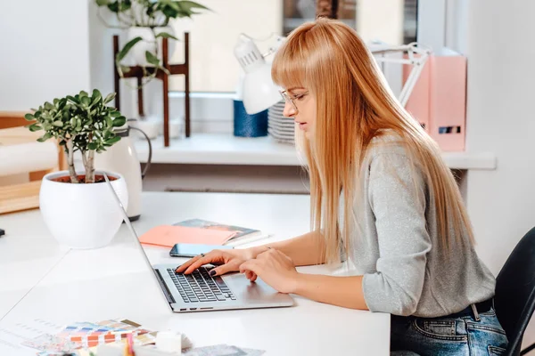 Concentrada em seu trabalho, a funcionária do escritório se senta à mesa — Fotografia de Stock