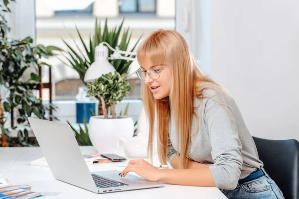 Femme entrepreneure enthousiaste s'assoit à table le jour dans un bureau moderne — Photo