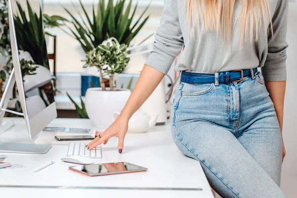 Mulher elegante posa sentada em uma mesa há alguns dispositivos de escritório — Fotografia de Stock