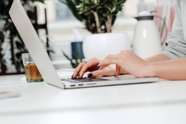 Modern ofisteki masada dizüstü bilgisayarın klavyesinde yazan kadın.