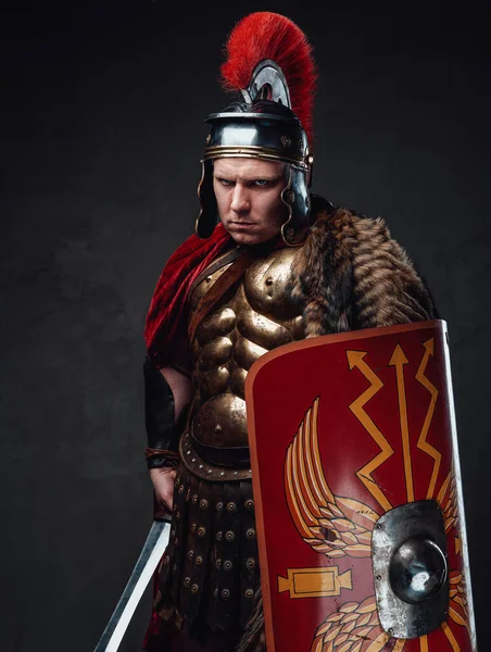 Ősi római katona dühös tekintettel a sötét háttér felé. — Stock Fotó