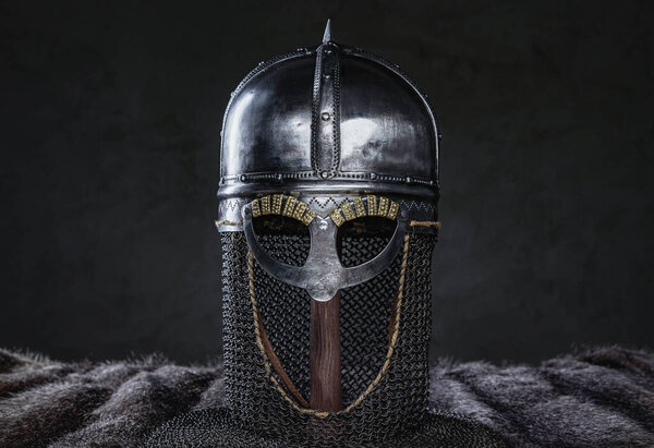 Studio shot of isolated in dark background antique knight helmet and fur.