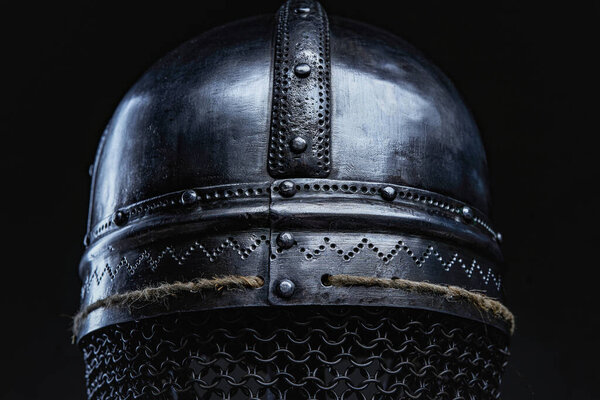 Closeup back view of authentic iron helmet with chain mail against dark background.
