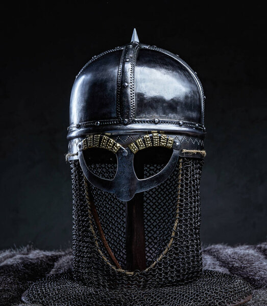 Medieval protective headwear of knight with chainmail against dark background.