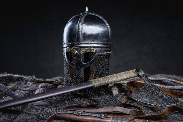 Studio shot of knight antique armored clothing with belt and axe against dark background.