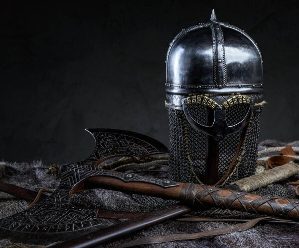 Studio shot of knight antique armored clothing with belt and axe against dark background.