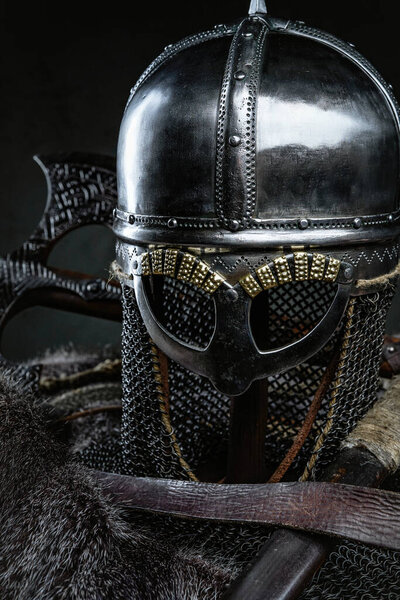 Isolated in dark background knight iron helmet around axes belt and fur.