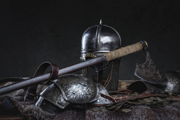 Isolated in dark background antique knight armor with helmet on fur with axe.