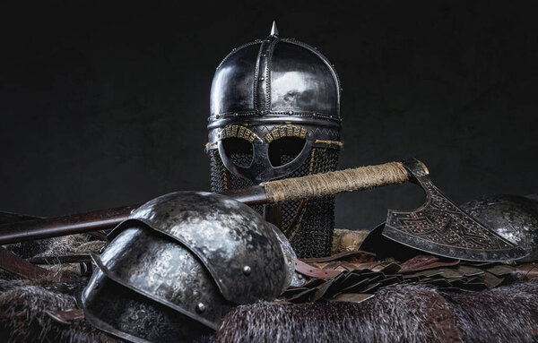 Isolated in dark background antique knight armor with helmet on fur with axe.