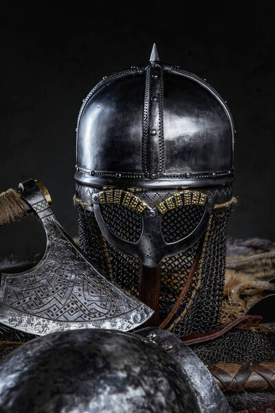 Combative knight suit of armor with helmet and axe against dark background.