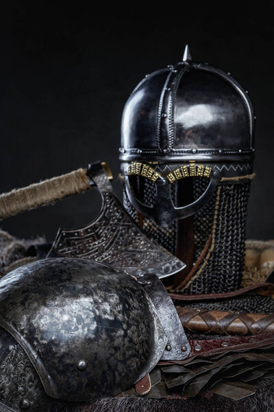 Combative knight suit of armor with helmet and axe against dark background.