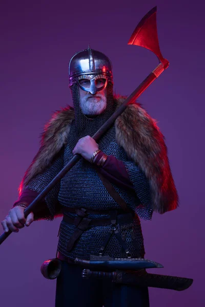 Middeleeuwse oude krijger met bijl tegen paarse achtergrond — Stockfoto