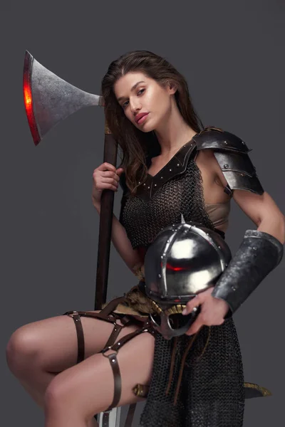 Nordic amazon with axe and helmet sitting on chair — Stock Photo, Image