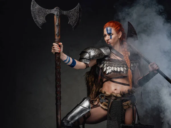 Mulher guerreira do norte em armadura de aço segurando machados em fumaça — Fotografia de Stock