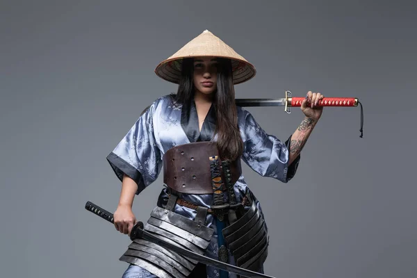 Young female warrior with samurai swords and bamboo hat — Stock Photo, Image