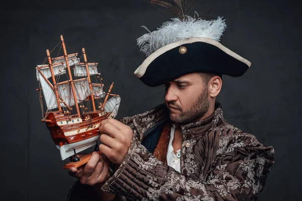 Потрясающий пират смотрит на маленький игрушечный корабль — стоковое фото