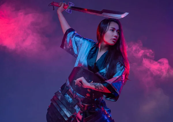 Östra kvinna med samuraj svärd i strid hållning — Stockfoto
