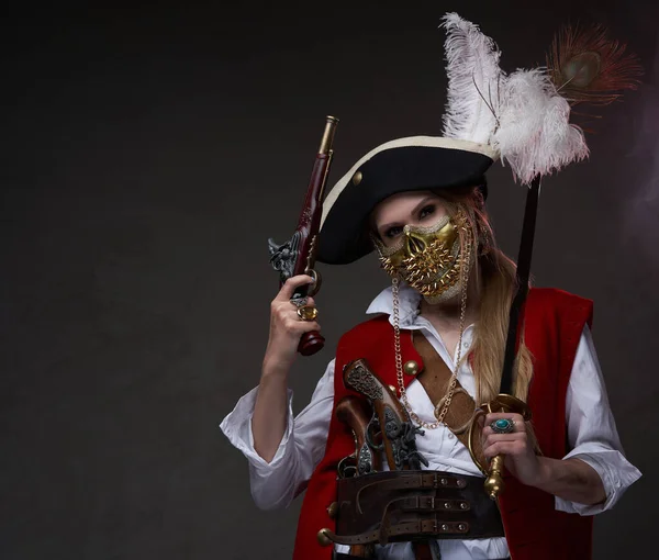 Modelo feminina vestida em terno de pirata com sabre e arma — Fotografia de Stock