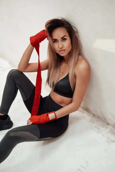Fitness kobieta siedzi na podłodze pod ścianą — Zdjęcie stockowe