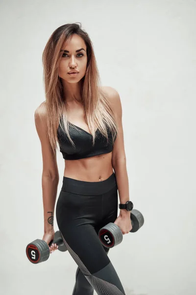 Modelo de fitness segurando halteres contra fundo branco — Fotografia de Stock