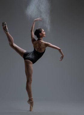 Zarif balerin stüdyoda toz püskürtüyor ve dans ediyor.