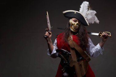 Dövmeli kadın korsan kılıçla ve silahla poz veriyor.